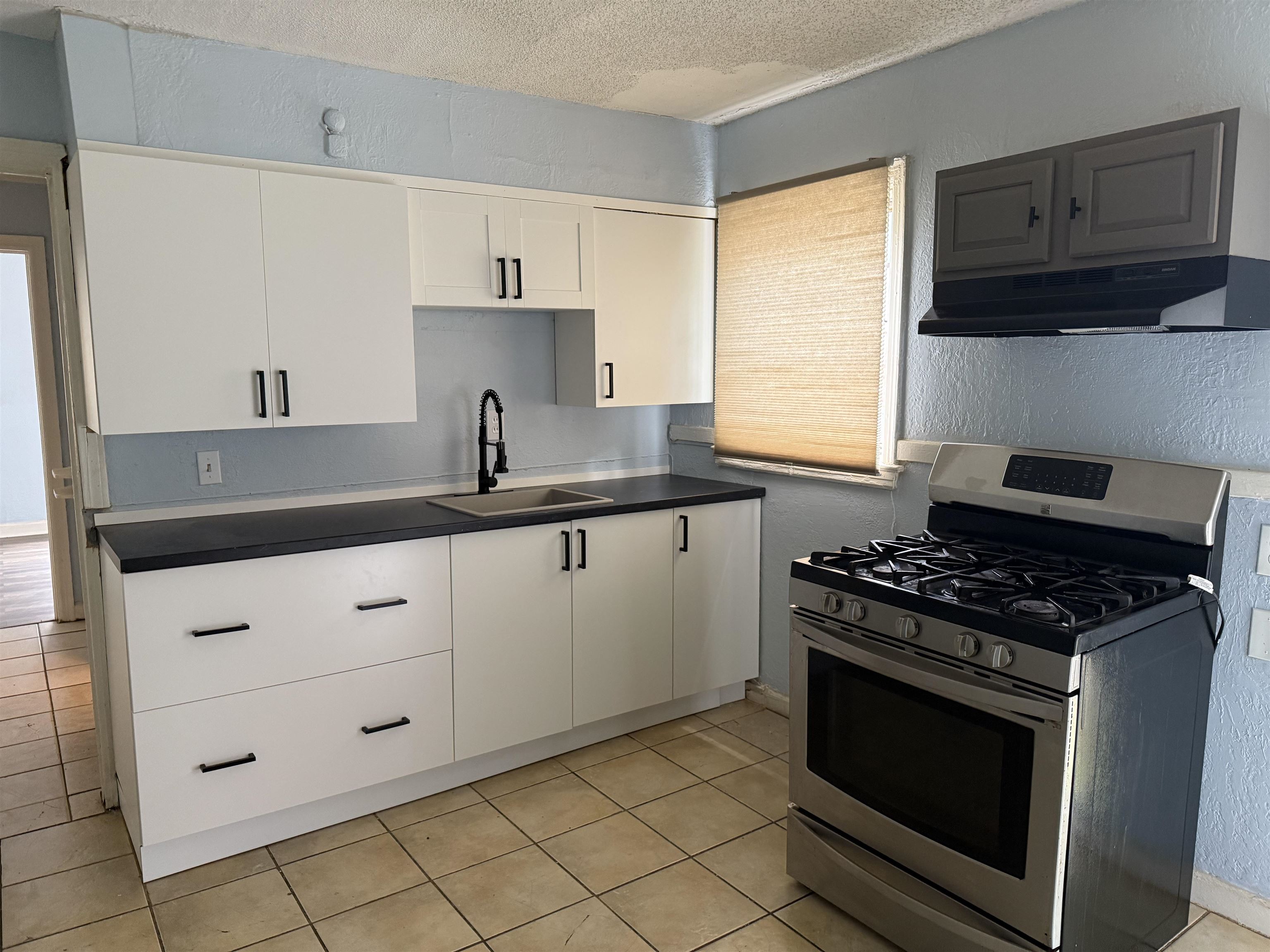 1248 Meda Street Memphis, TN 38114 - Photo 6 of 24 Kitchen featuring a textured wall, stainless steel gas range oven, dark countertops, a textured ceiling, and light tile patterned floors