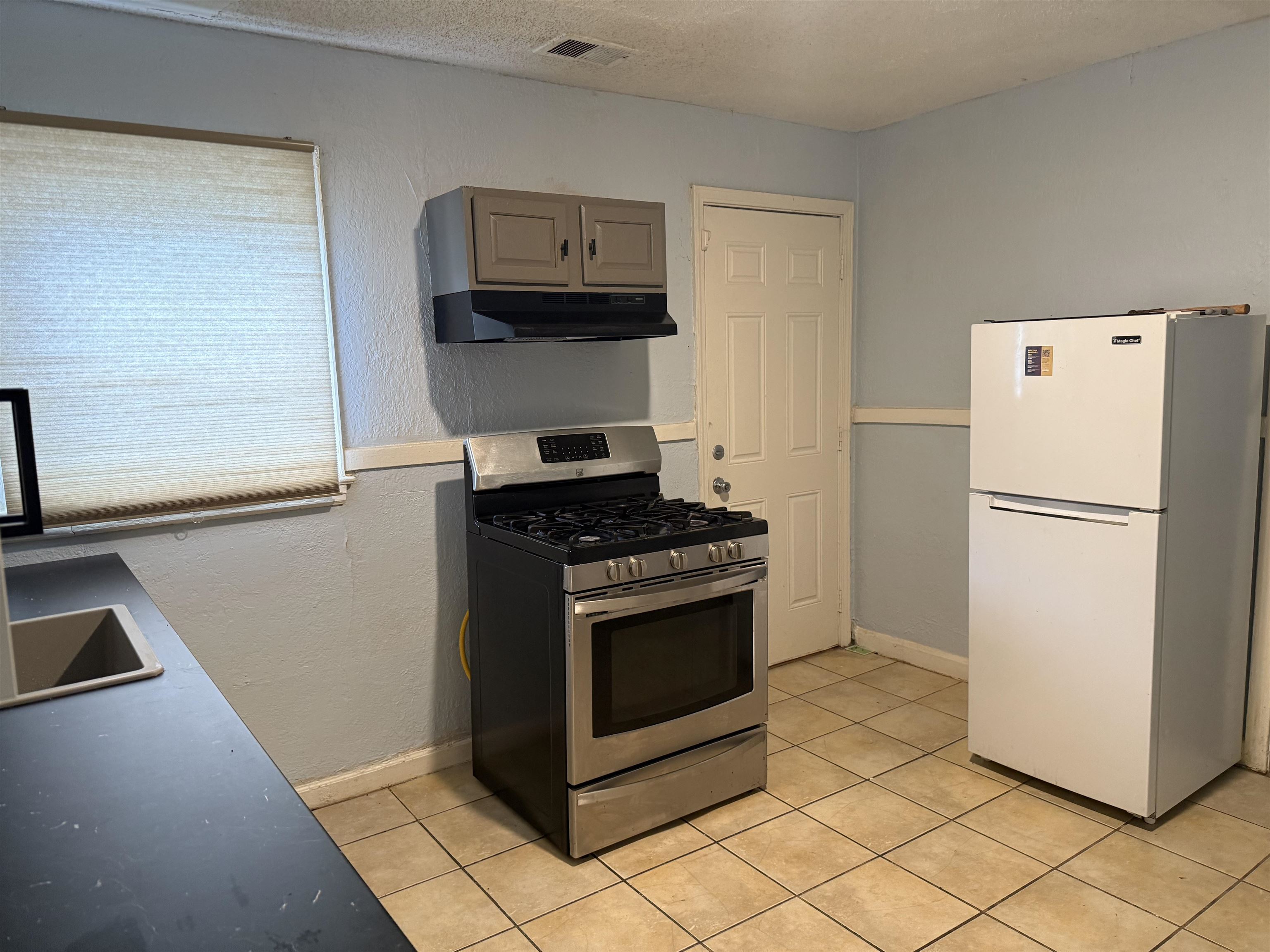 1248 Meda Street Memphis, TN 38114 - Photo 7 of 24 Kitchen featuring gas range, freestanding refrigerator, a textured ceiling, light tile patterned floors, and a textured wall