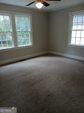 an empty room with windows and fan