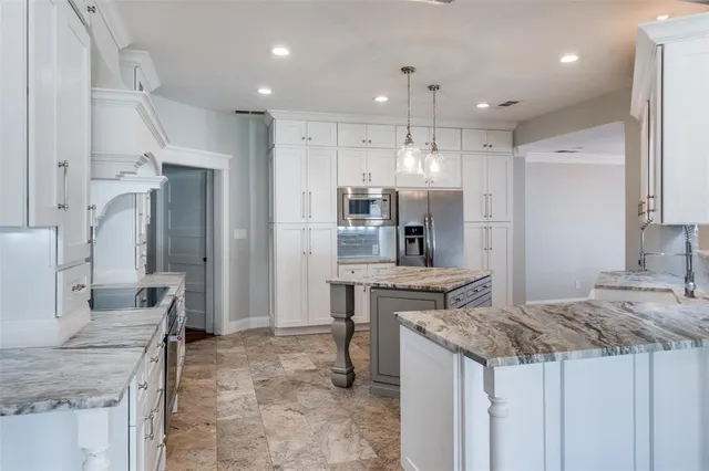 a kitchen with kitchen island granite countertop a table and stainless steel appliances