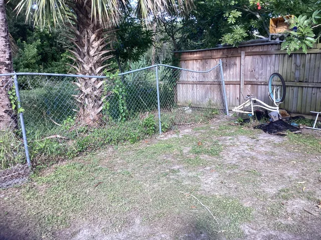 a backyard of a house with large trees and wooden fence