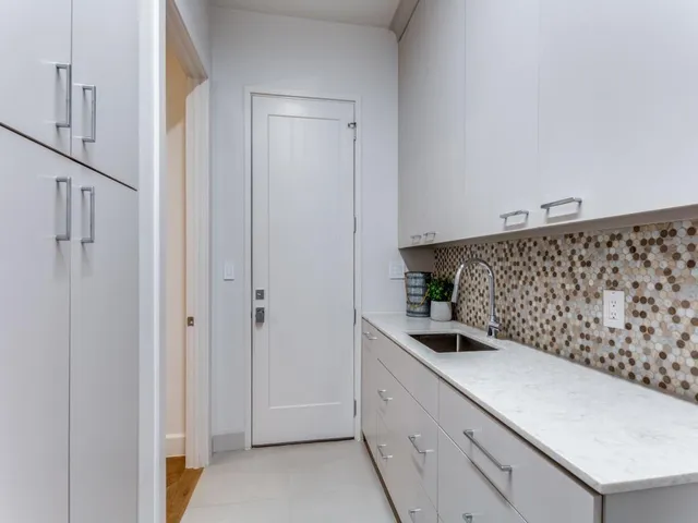 a kitchen with white cabinets and sink