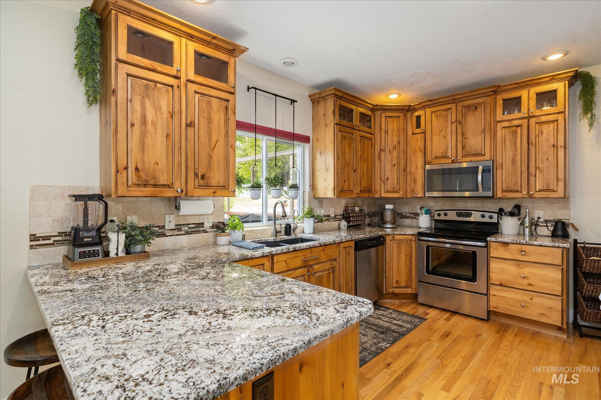 1140 Edgemont Road Emmett, ID 83617 - Photo 5 of 50 Kitchen featuring light-tone wood cabinetry, speckled countertops, stainless steel appliances, and wood-finish flooring