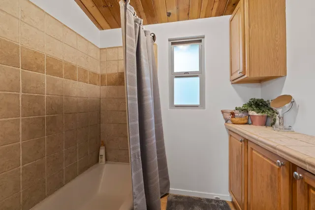 a bathroom with a granite countertop sink a mirror and shower