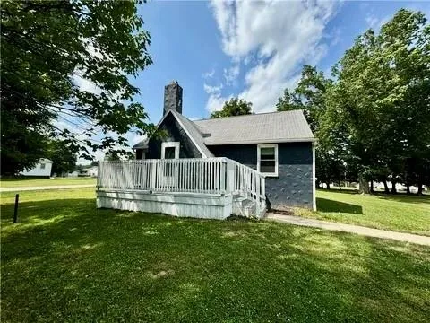 a view of a house with a yard deck and a large tree