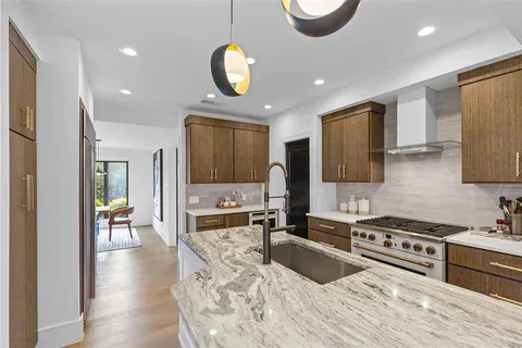 a kitchen with stainless steel appliances granite countertop a sink dishwasher stove and refrigerator with wooden floor
