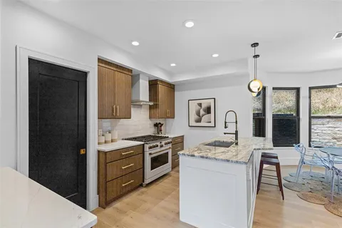 a kitchen with stainless steel appliances granite countertop a stove top oven a sink dishwasher a dining table and chairs with wooden floor