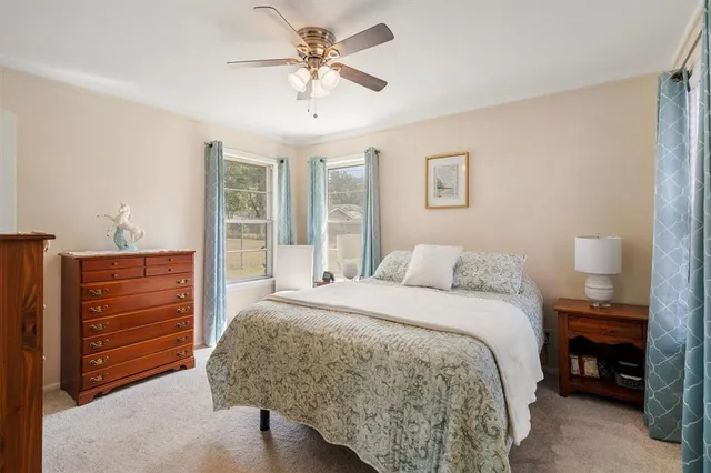 a spacious bedroom with a bed a ceiling fan and a dresser