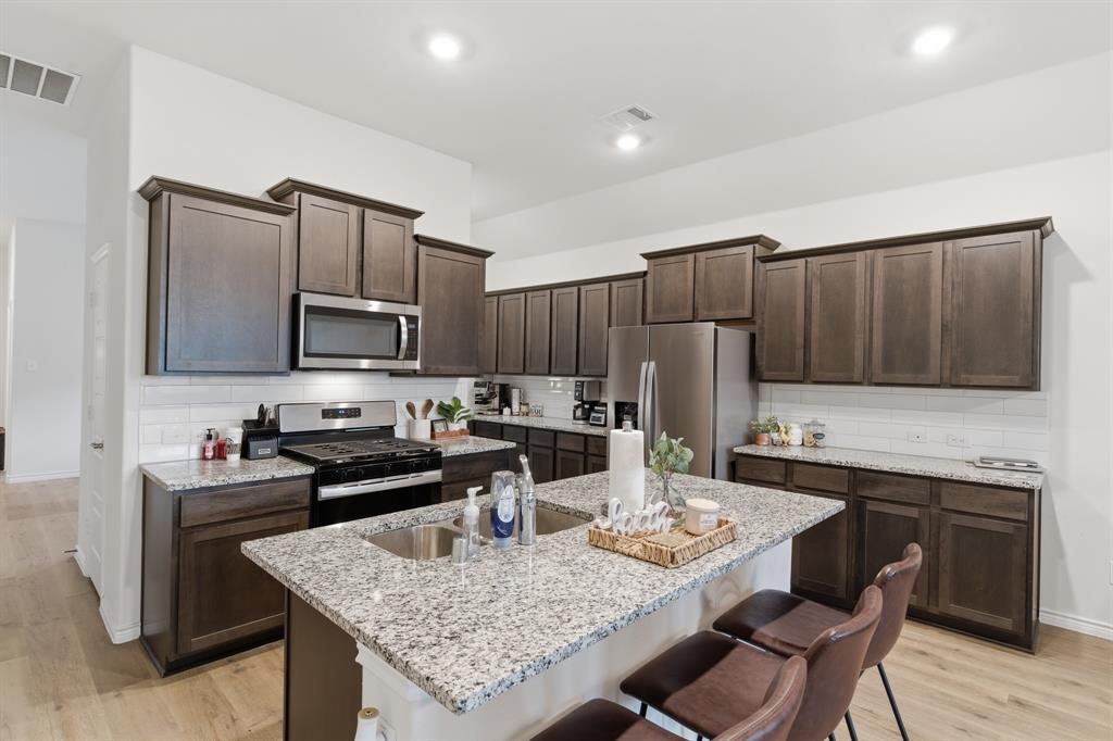 727 Fort Lane Fate, TX 75189 - Photo 8 of 19 a kitchen with granite countertop stainless steel appliances cabinets a sink and a island