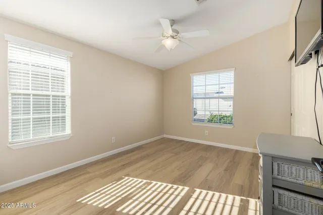 a view of an empty room with a window and wooden floor