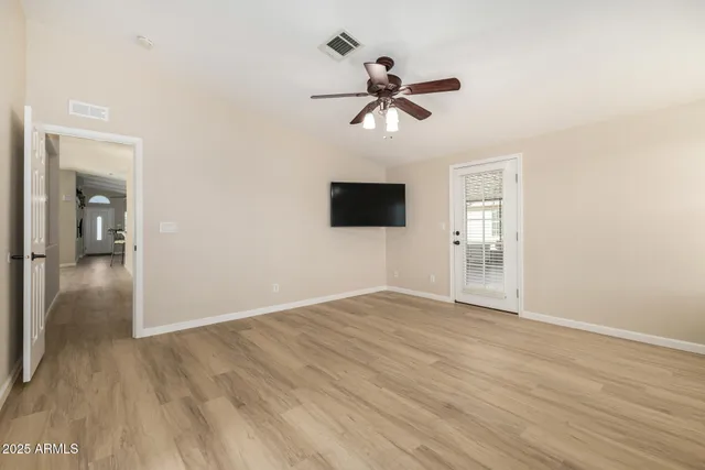 a view of empty room with wooden floor and fan
