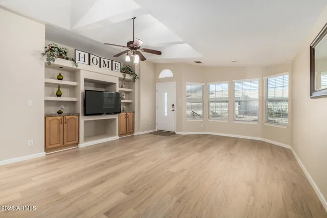 a view of an empty room with a window and wooden floor