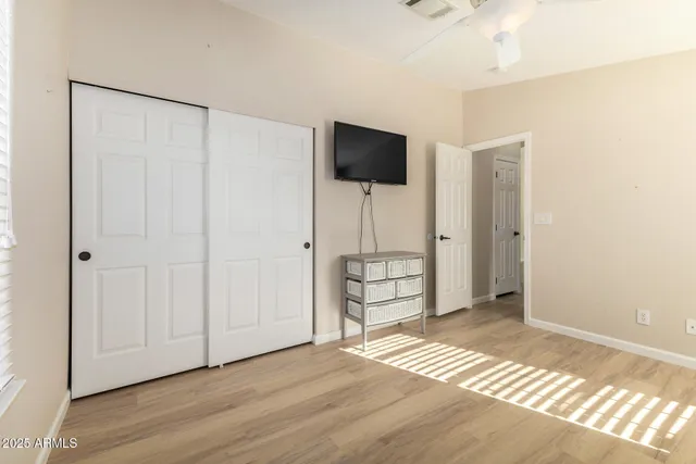 a view of empty room with wooden floor and fan