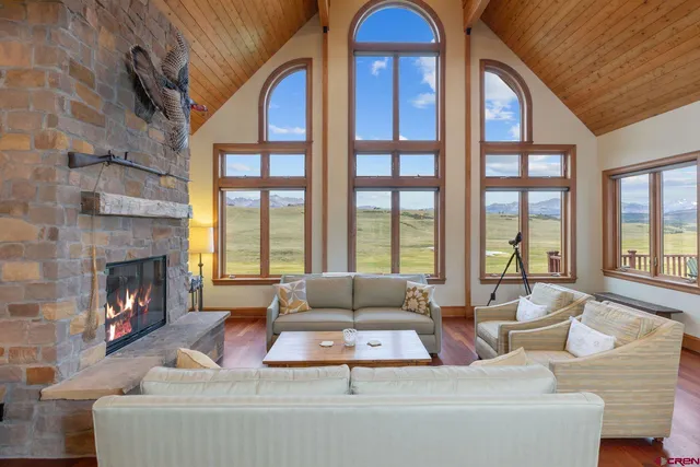 a living room with furniture large windows and fireplace