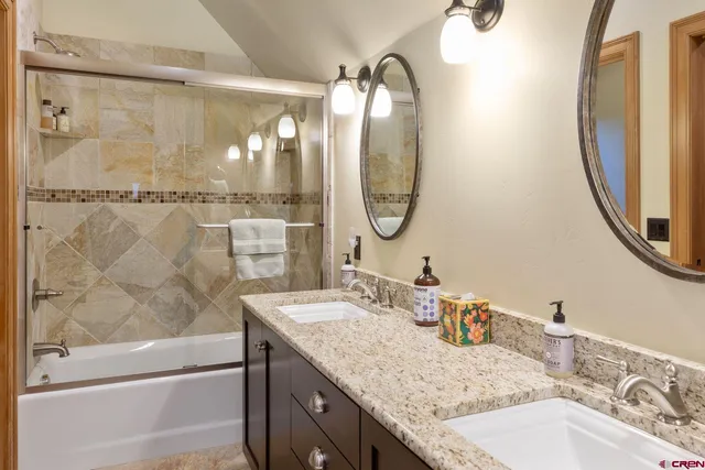 a view of a hallway with wooden floor and a bathroom