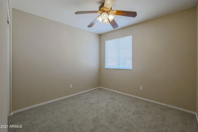 an empty room with a window and a fan