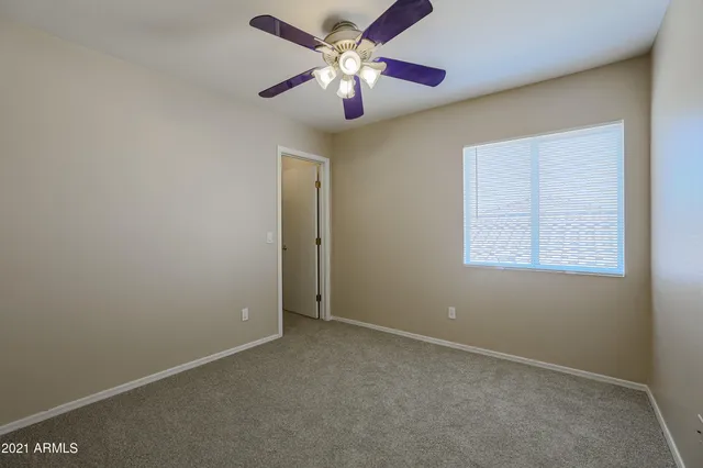 an empty room with a chandelier fan and windows