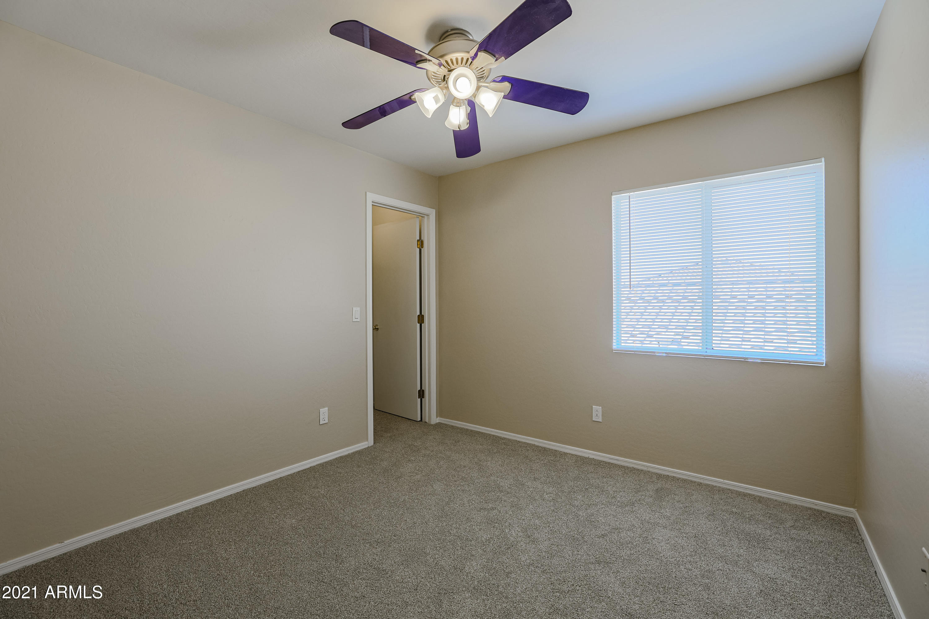 4349 North 111th Lane Phoenix, AZ 85037 - Photo 15 of 18 an empty room with a chandelier fan and windows