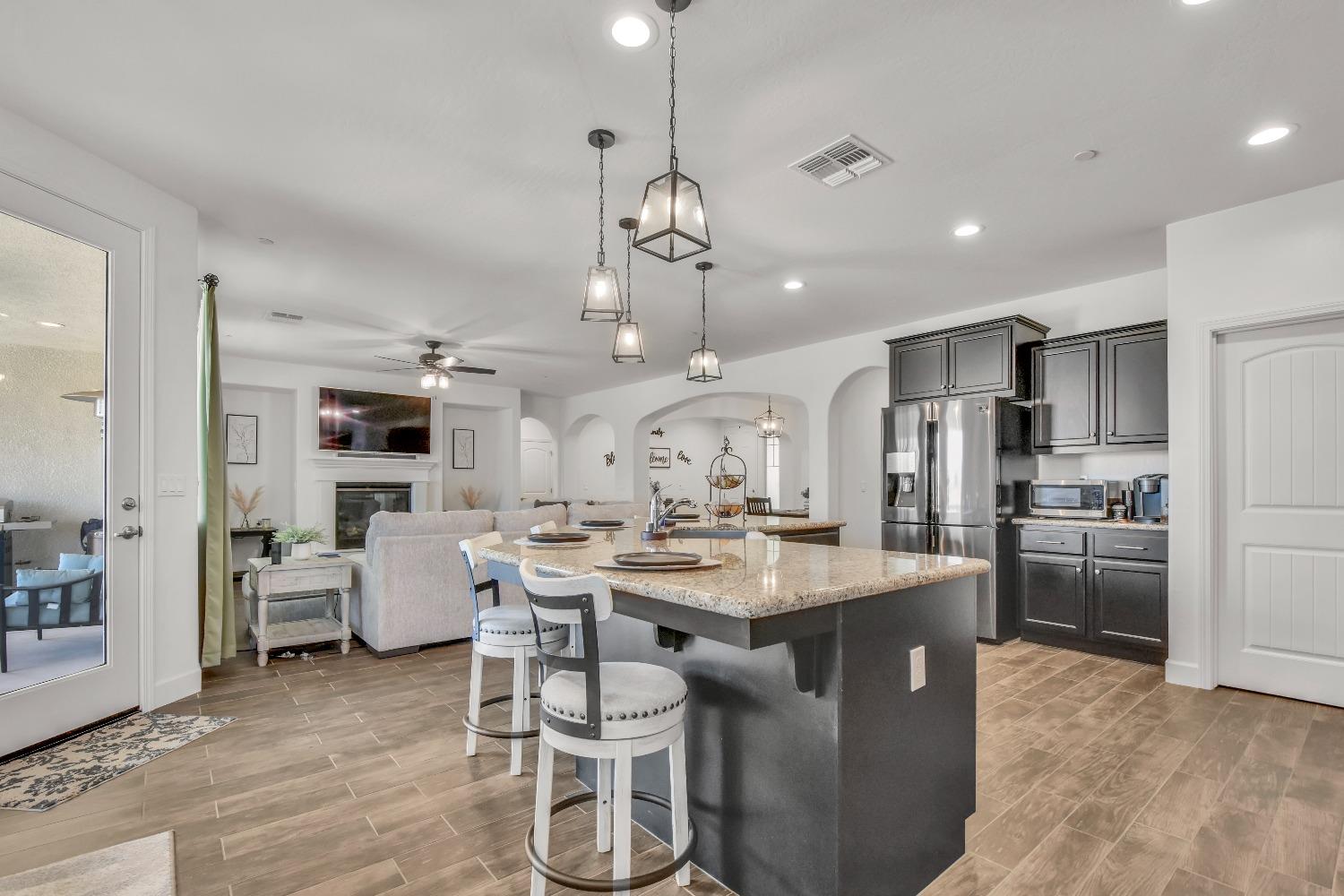 400 Ridge Creek Estates Way Dinuba, CA 93618 - Photo 11 of 49 a kitchen with stainless steel appliances kitchen island granite countertop a stove a refrigerator a oven a dining table and chairs with wooden floor