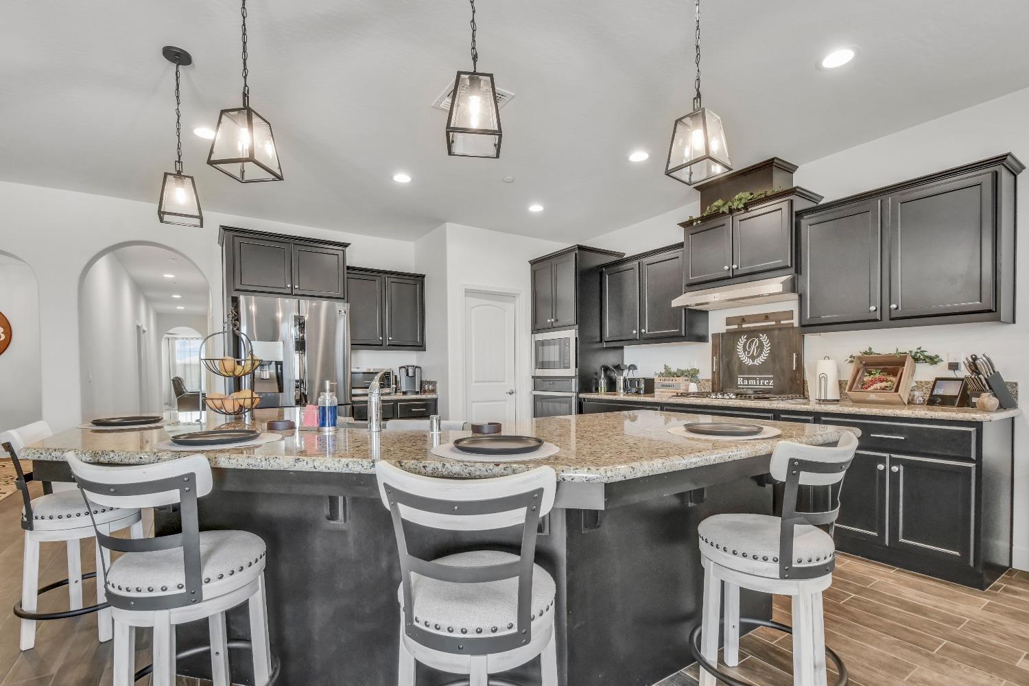 400 Ridge Creek Estates Way Dinuba, CA 93618 - Photo 12 of 49 a kitchen with sink a stove and chairs with wooden floor