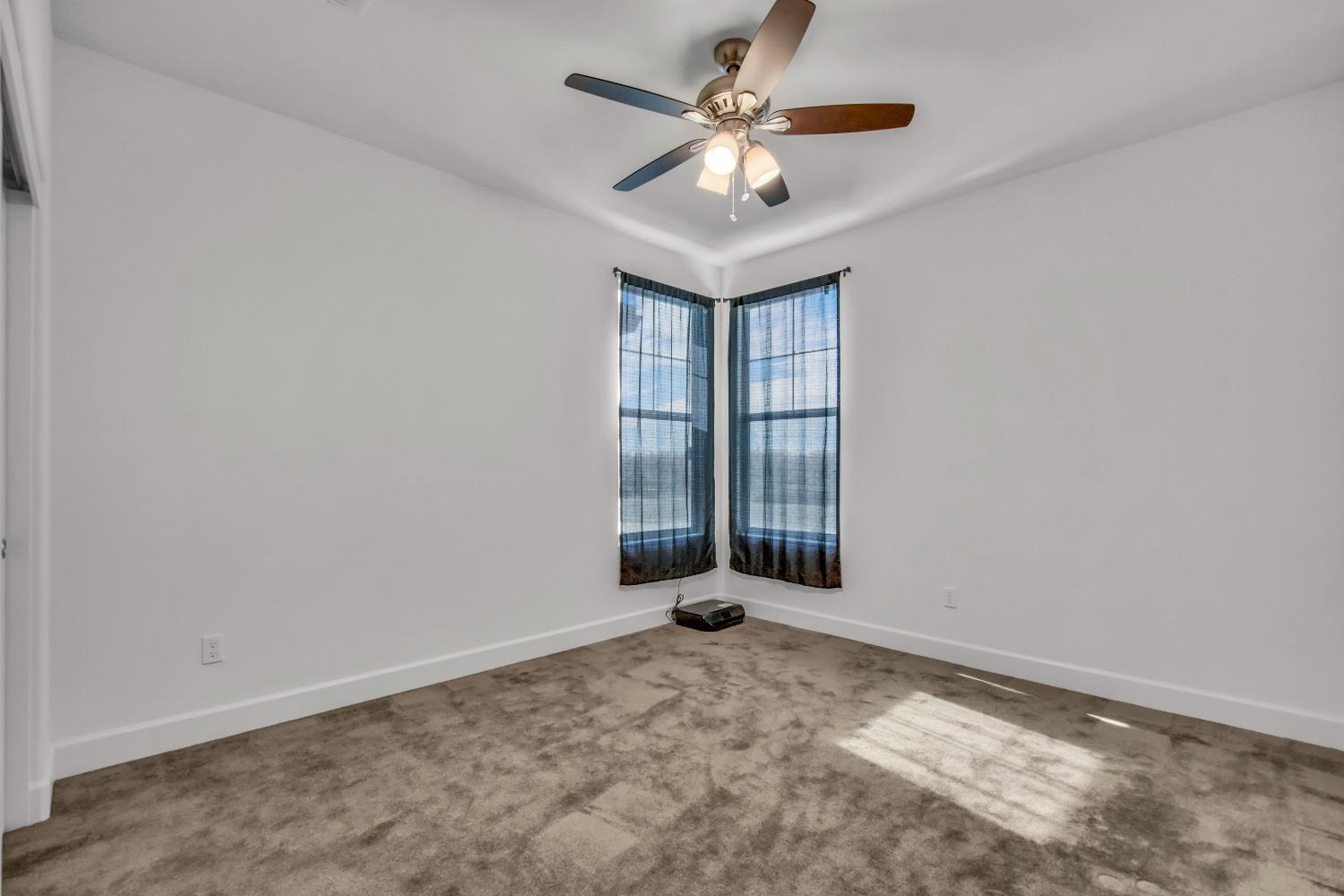 400 Ridge Creek Estates Way Dinuba, CA 93618 - Photo 22 of 49 an empty room with chandelier fan and windows