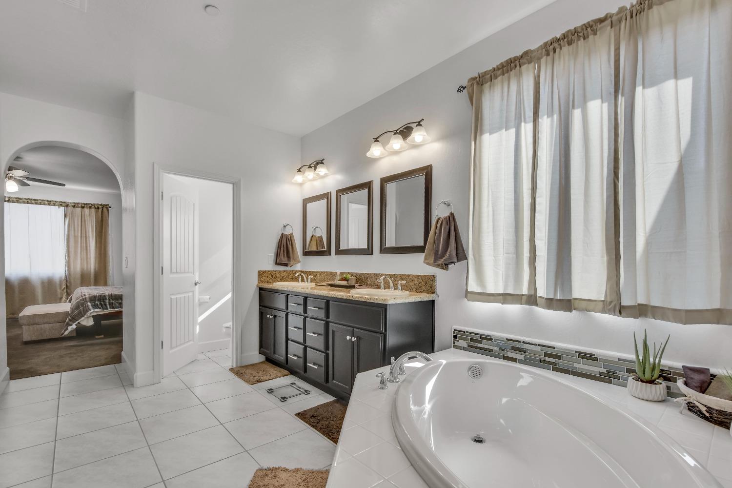 400 Ridge Creek Estates Way Dinuba, CA 93618 - Photo 32 of 49 a large bathroom with a tub sink and mirror