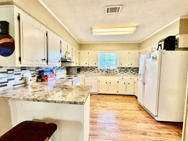 a kitchen with stainless steel appliances granite countertop a refrigerator a stove and a sink with wooden floor