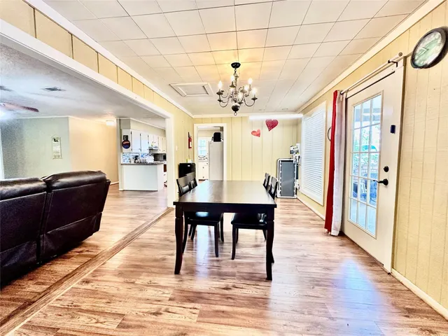a view of a dining room and livingroom with furniture wooden floor a chandelier