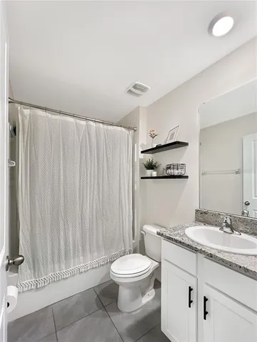 a bathroom with a granite countertop sink a toilet and a shower