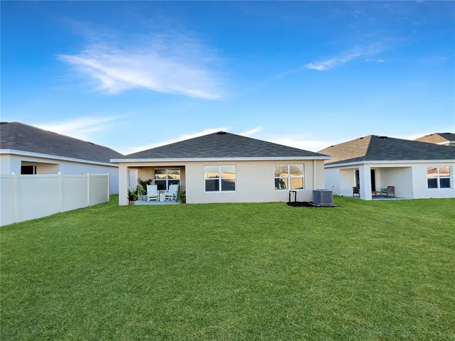 a view of a yard in front of a house with plants and large tree