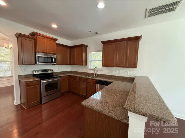 a kitchen with granite countertop wooden cabinets and stainless steel appliances