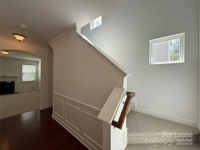 a view of an empty room with wooden floor and a chandelier