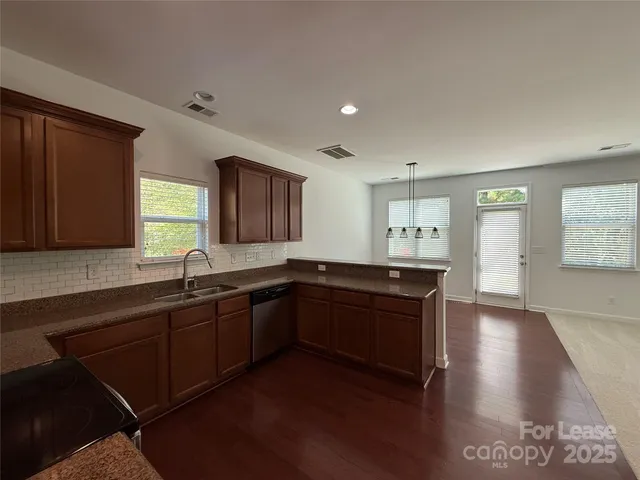 a kitchen with granite countertop a stove a sink and a refrigerator