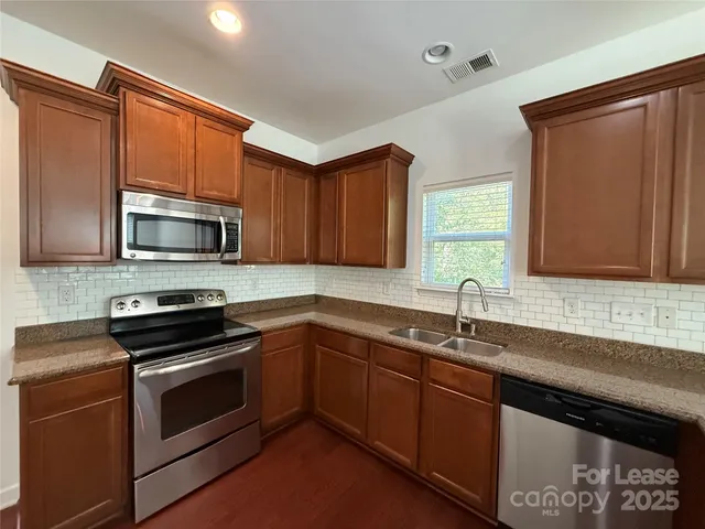a kitchen with sink a microwave a stove and cabinets
