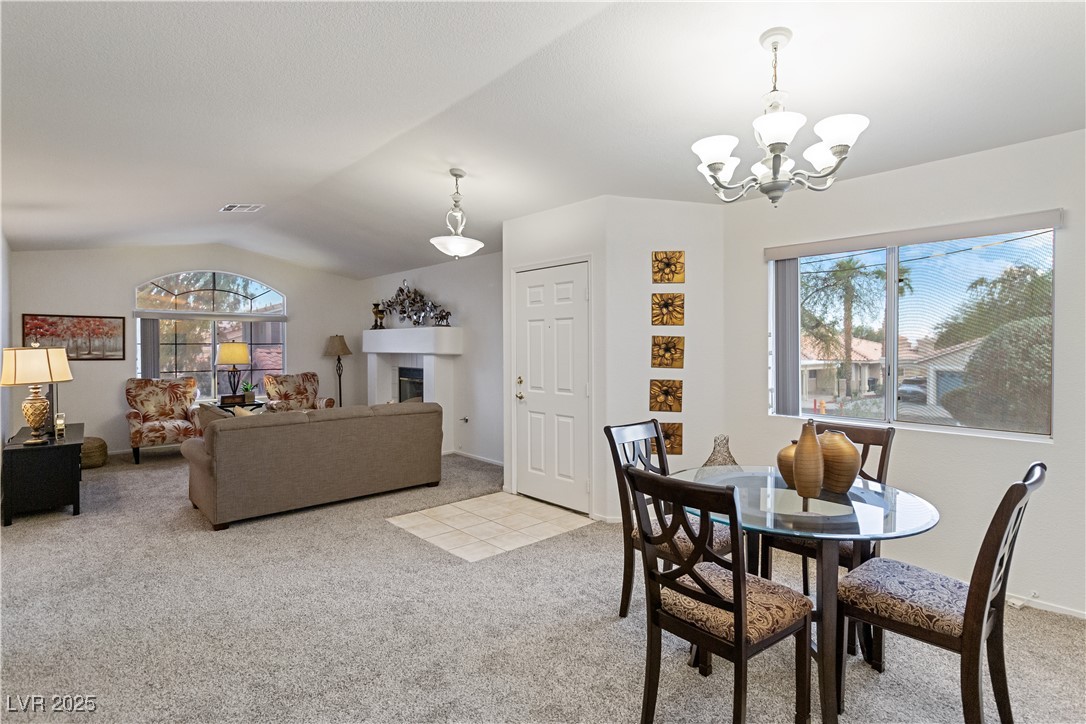 2297 Camel Mesa Drive Laughlin, NV 89029 - Photo 18 of 98 Dining room with light carpet, lofted ceiling, a chandelier, and a tiled fireplace