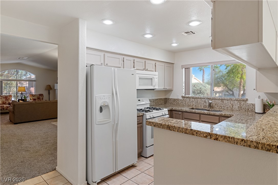 2297 Camel Mesa Drive Laughlin, NV 89029 - Photo 32 of 98 Kitchen with white appliances, light colored carpet, light tile patterned floors, light stone counters, and recessed lighting