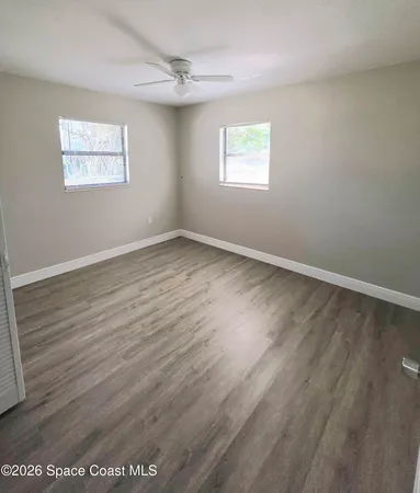 a view of an empty room with wooden floor and window