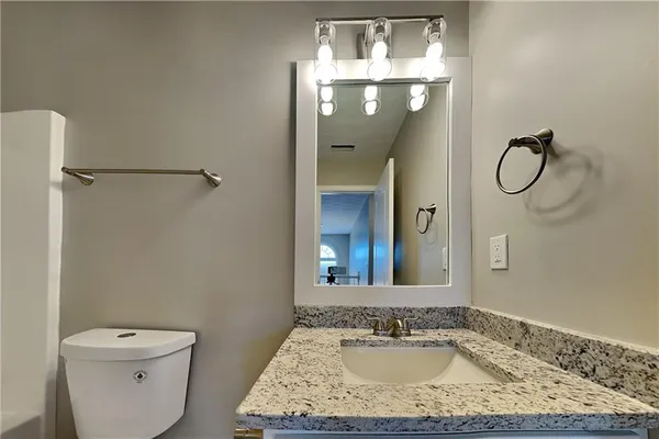 a bathroom with a granite countertop sink a toilet and a mirror