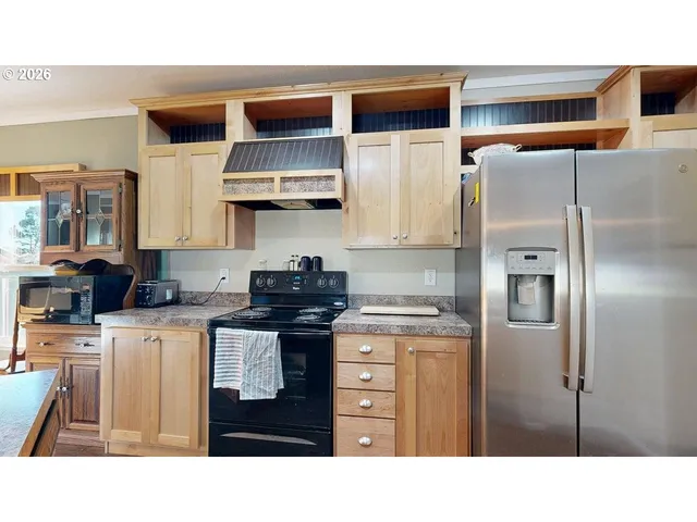 a kitchen with stainless steel appliances granite countertop a refrigerator a stove and a sink with wooden cabinets