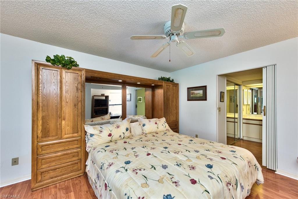 14730 Eagle Ridge Drive, Unit 122 Fort Myers, FL 33912 - Photo 12 of 27 a bedroom with a large bed and a chandelier