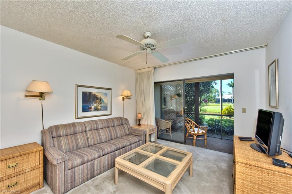 14730 Eagle Ridge Drive, Unit 122 Fort Myers, FL 33912 - Photo 14 of 27 a living room with furniture a chandelier and a flat screen tv