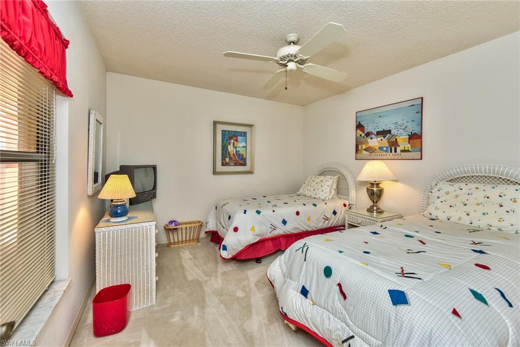 14730 Eagle Ridge Drive, Unit 122 Fort Myers, FL 33912 - Photo 18 of 27 a bedroom with two beds and a chandelier