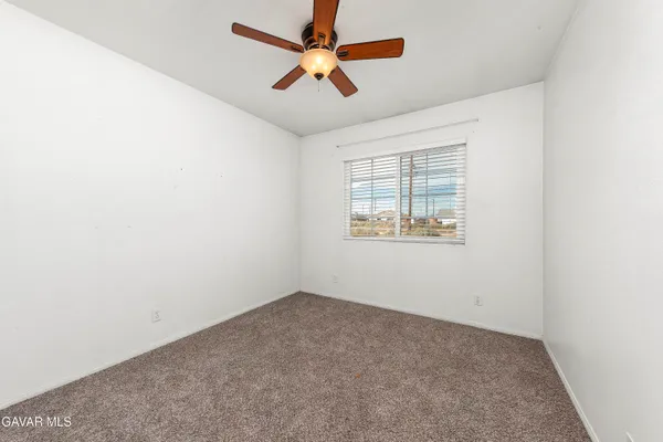 an empty room with a window and a ceiling fan