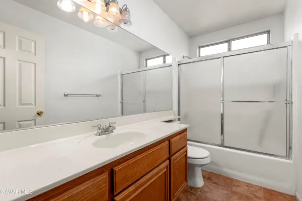 a bathroom with a sink a toilet a mirror and shower