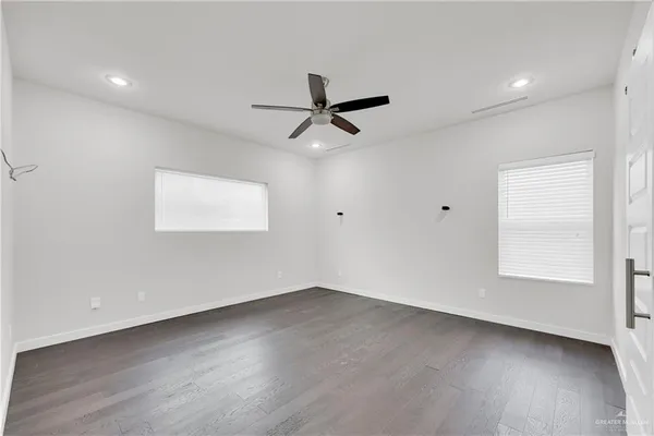a view of an empty room with cabinet and a ceiling fan