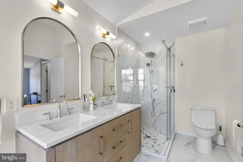 a spacious bathroom with a double vanity sink toilet mirror and double