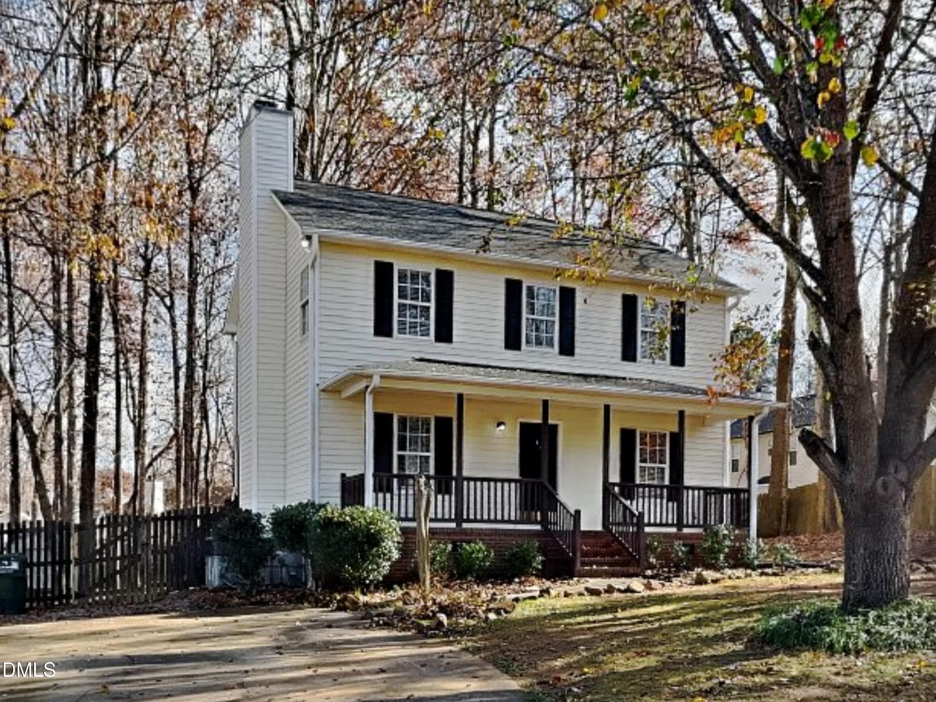 a front view of a house with lots of trees and plants