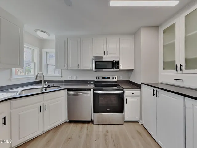 a kitchen with stainless steel appliances granite countertop a sink stove and white cabinets