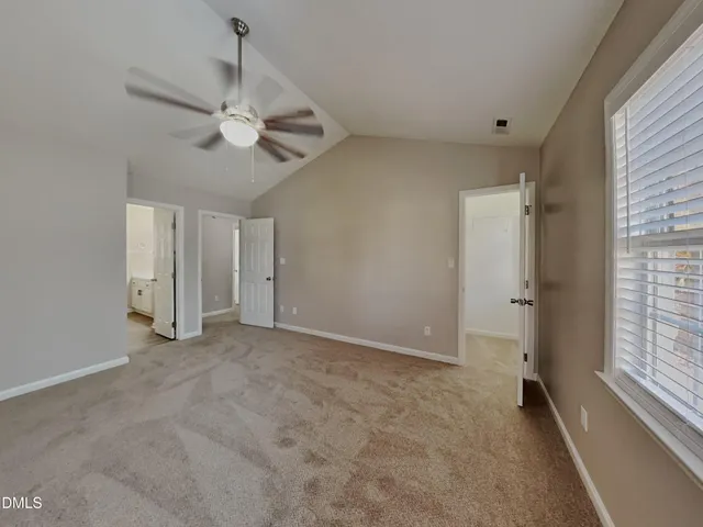 an empty room with chandelier fan and windows