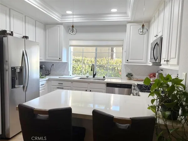 a kitchen with stainless steel appliances a sink a table and a refrigerator